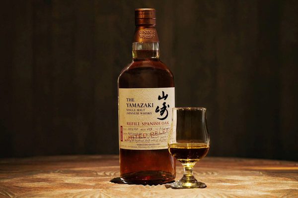 Yamazaki Refill Spanish Oak eine Flasche Yamazaki Refill Spanish Oak nebst Glas auf einer Holzplatte